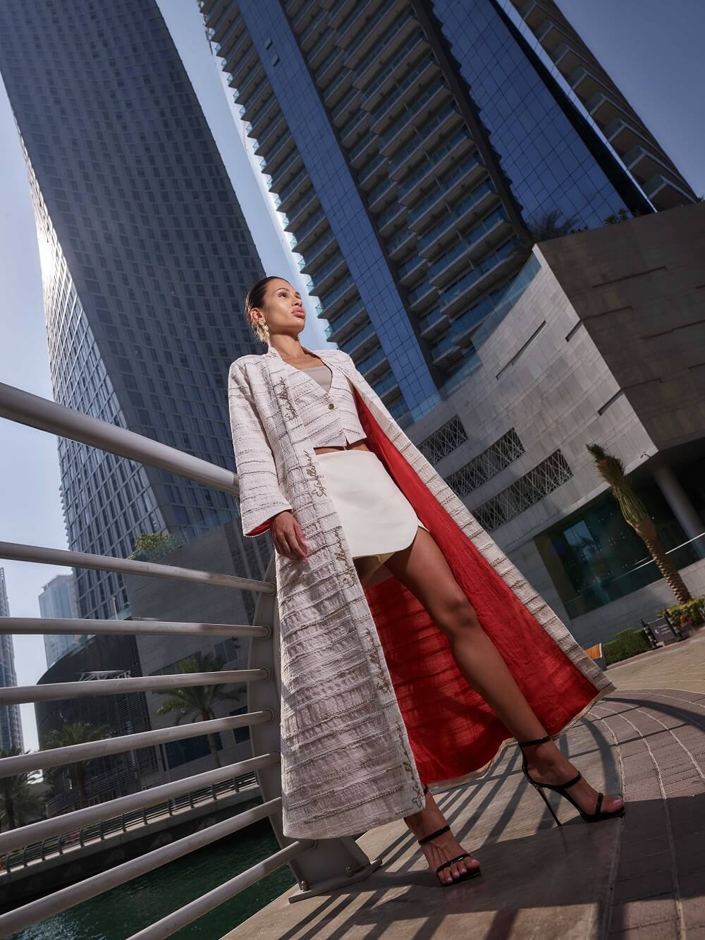 Woman in a long coat from the signature collection of Kashesh Global standing in front of modern buildings | Luxury Sustainable Women's Fashion in Dubai